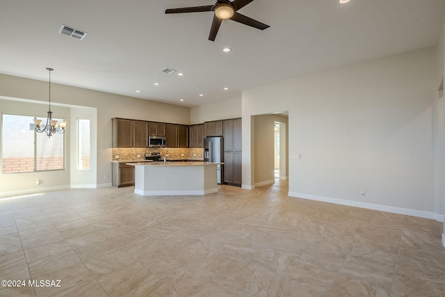 kitchen featuring pendant lighting, ceiling fan with notable chandelier, light stone countertops, tasteful backsplash, and stainless steel appliances