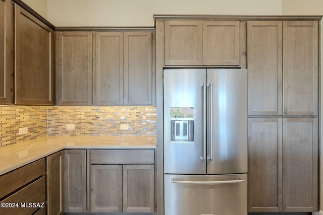 kitchen with tasteful backsplash, stainless steel fridge with ice dispenser, and light stone counters