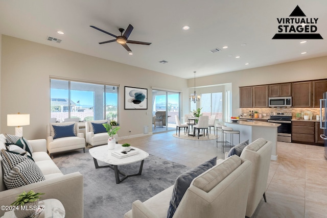 tiled living room featuring ceiling fan with notable chandelier and a wealth of natural light