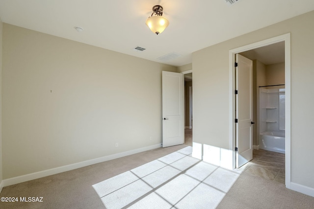 unfurnished bedroom featuring ensuite bathroom and light colored carpet