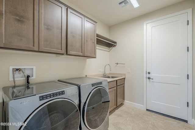 laundry room with sink, light tile patterned floors, cabinets, and independent washer and dryer