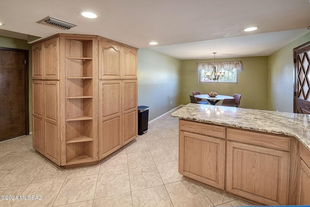 kitchen with pendant lighting, light brown cabinetry, light tile patterned floors, light stone countertops, and an inviting chandelier