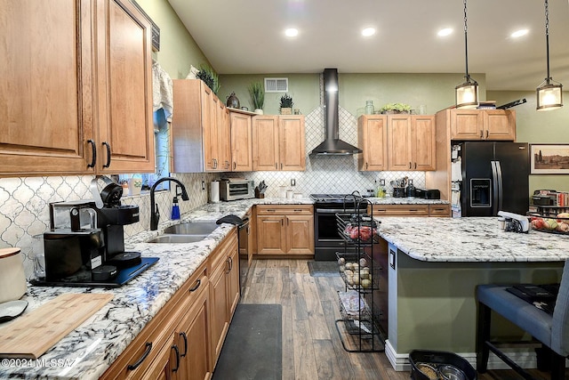 kitchen with visible vents, black fridge with ice dispenser, wall chimney range hood, stainless steel range oven, and a sink