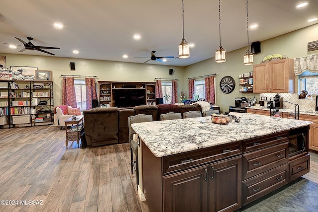 kitchen with a center island, black microwave, dark brown cabinets, dark hardwood / wood-style floors, and backsplash