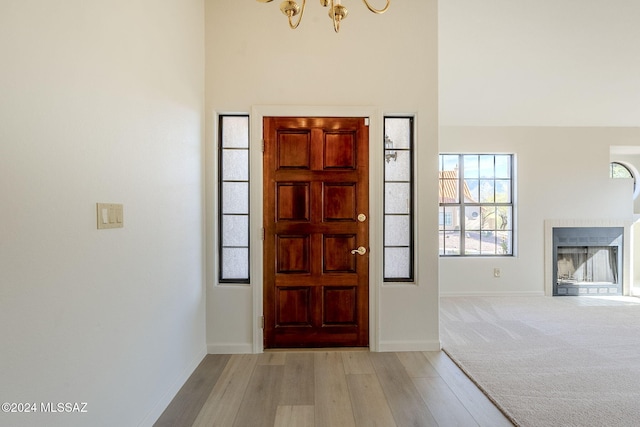 entrance foyer featuring a chandelier, a towering ceiling, and light hardwood / wood-style flooring