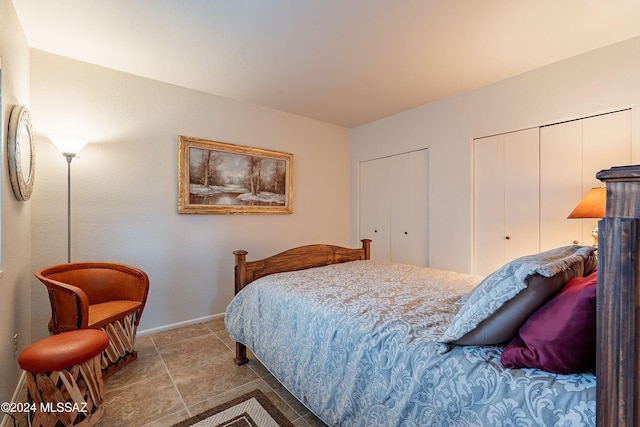 bedroom with tile patterned flooring and two closets