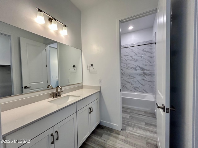 bathroom with bathing tub / shower combination, wood finished floors, vanity, and baseboards