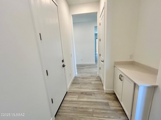 corridor with light wood-style flooring and baseboards
