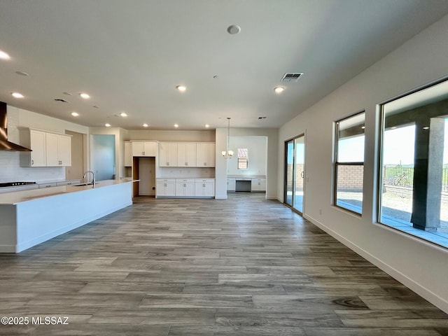 kitchen featuring tasteful backsplash, recessed lighting, white cabinetry, visible vents, and a sink