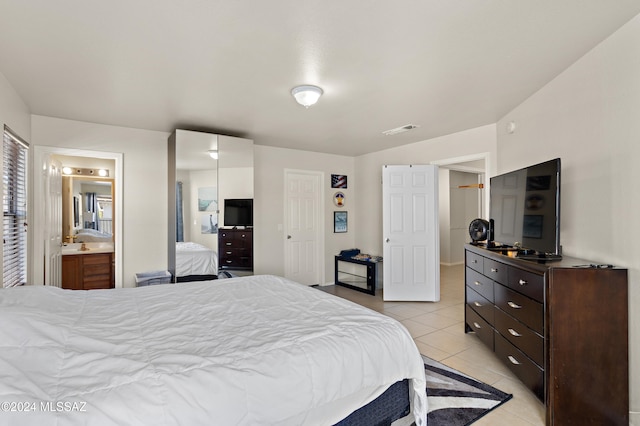 tiled bedroom featuring connected bathroom and a closet