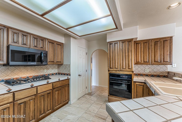 kitchen featuring backsplash, tile counters, stainless steel appliances, and sink