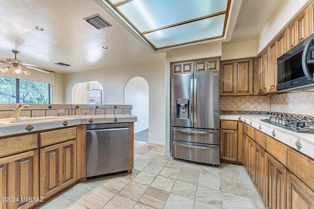 kitchen with backsplash, ceiling fan, sink, and appliances with stainless steel finishes