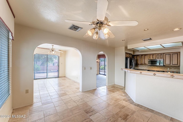 kitchen featuring decorative backsplash, ceiling fan, stainless steel appliances, and a textured ceiling