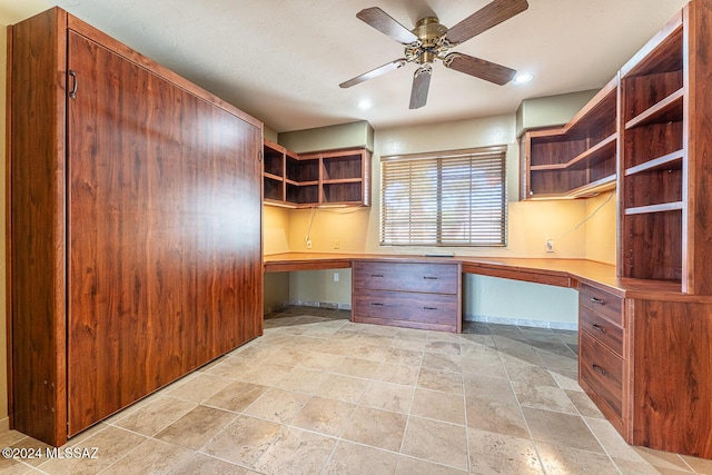 unfurnished office featuring ceiling fan and built in desk