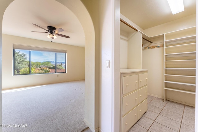 walk in closet with light carpet and ceiling fan