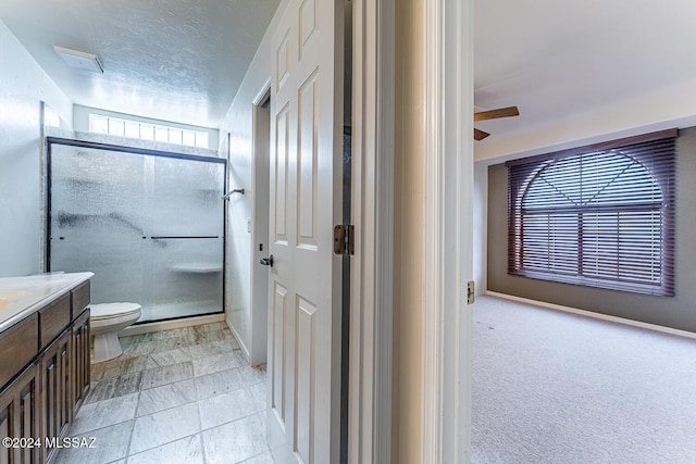 bathroom with ceiling fan, a shower with door, vanity, and toilet