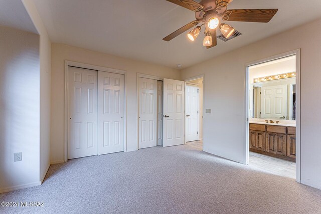 unfurnished bedroom with connected bathroom, light colored carpet, and ceiling fan