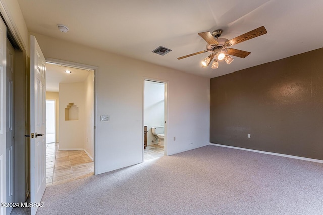 unfurnished bedroom featuring a closet, light colored carpet, ensuite bath, and ceiling fan