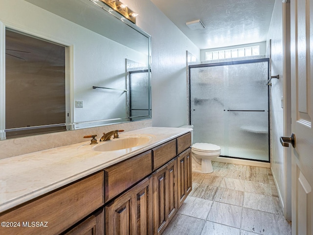 bathroom with a textured ceiling, vanity, toilet, and walk in shower