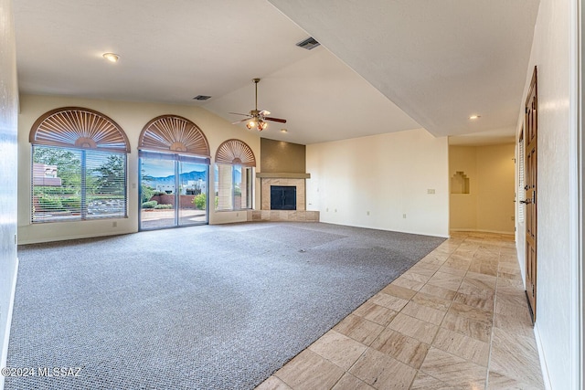 unfurnished living room with light colored carpet, ceiling fan, lofted ceiling, and a tiled fireplace