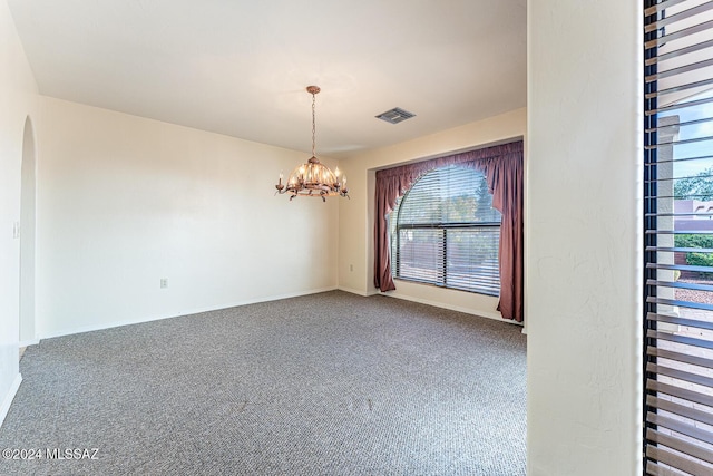 empty room with carpet floors and an inviting chandelier