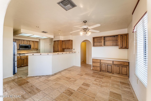 kitchen featuring decorative backsplash, ceiling fan, kitchen peninsula, and stainless steel appliances