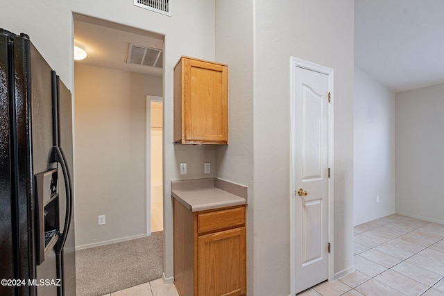 kitchen featuring light tile patterned floors and black refrigerator with ice dispenser