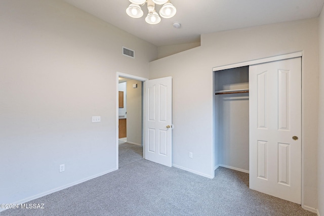 unfurnished bedroom with a closet, carpet floors, and a chandelier