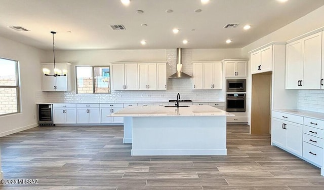 kitchen featuring appliances with stainless steel finishes, beverage cooler, wall chimney exhaust hood, and visible vents