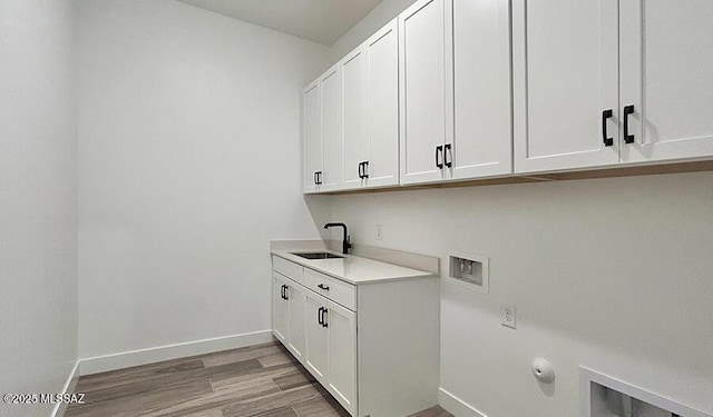 laundry area featuring cabinet space, a sink, baseboards, light wood finished floors, and hookup for a washing machine