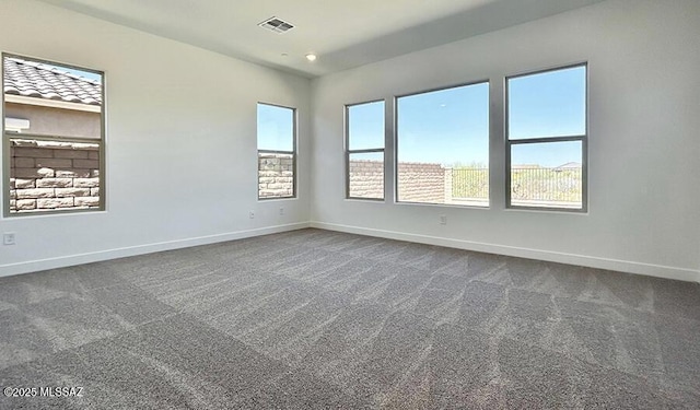unfurnished room with baseboards, dark carpet, and visible vents