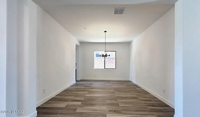 unfurnished dining area featuring visible vents, dark wood finished floors, baseboards, and a notable chandelier