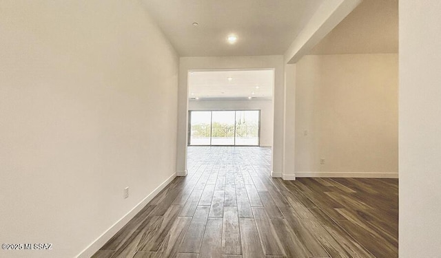 empty room featuring baseboards and dark wood-type flooring