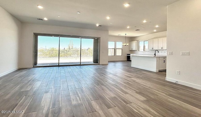 unfurnished living room with baseboards, recessed lighting, wood finished floors, and visible vents