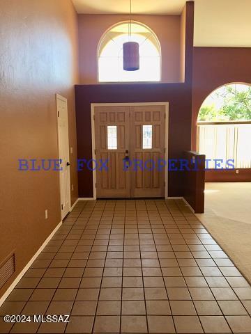 tiled entrance foyer featuring a towering ceiling and a healthy amount of sunlight