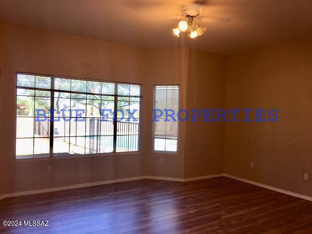 empty room with dark hardwood / wood-style flooring and an inviting chandelier