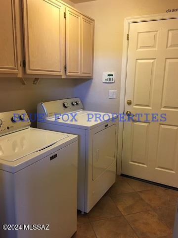 washroom featuring tile patterned floors, washing machine and dryer, and cabinets