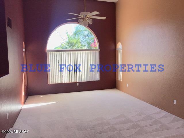 carpeted spare room featuring ceiling fan