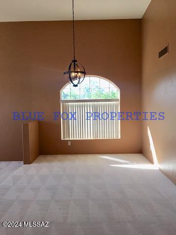 unfurnished room with light colored carpet and a chandelier