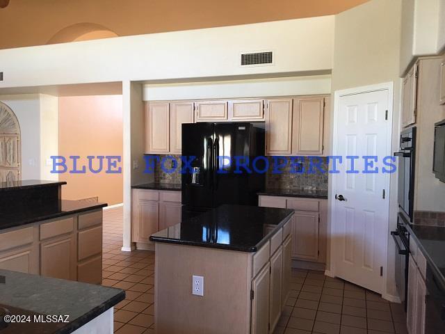 kitchen featuring decorative backsplash, a kitchen island, black appliances, and dark tile patterned flooring