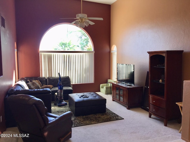 living room with ceiling fan, light carpet, and a high ceiling