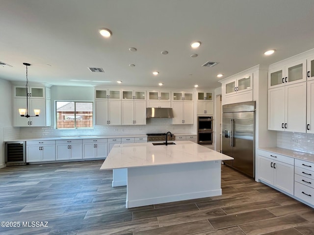 kitchen with wine cooler, appliances with stainless steel finishes, visible vents, and under cabinet range hood