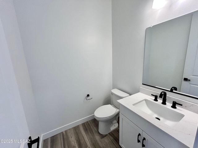 bathroom with vanity, baseboards, toilet, and wood finished floors