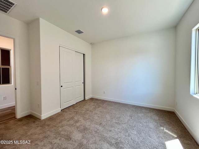 unfurnished bedroom featuring baseboards, carpet, and visible vents