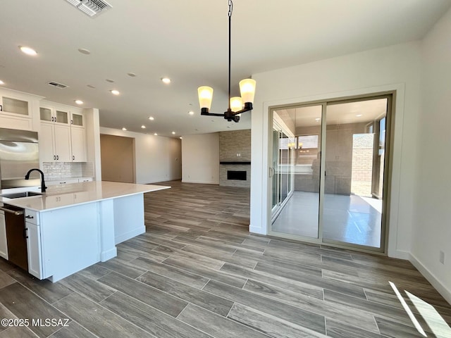 kitchen featuring open floor plan, light countertops, backsplash, white cabinetry, and visible vents