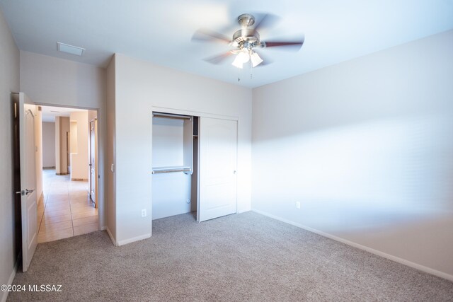 unfurnished bedroom featuring ceiling fan, light colored carpet, and a closet