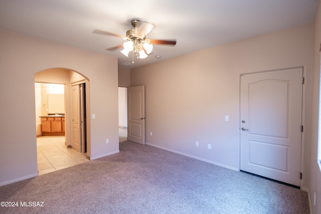 unfurnished bedroom with ceiling fan, light colored carpet, and connected bathroom