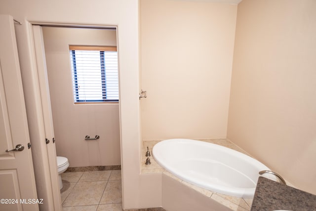 bathroom featuring tile patterned flooring, toilet, and a bath