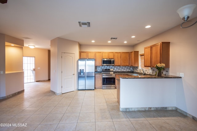 kitchen featuring decorative backsplash, dark stone countertops, light tile patterned flooring, kitchen peninsula, and stainless steel appliances