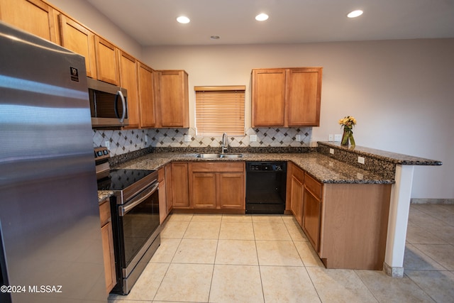 kitchen featuring kitchen peninsula, appliances with stainless steel finishes, tasteful backsplash, dark stone counters, and sink